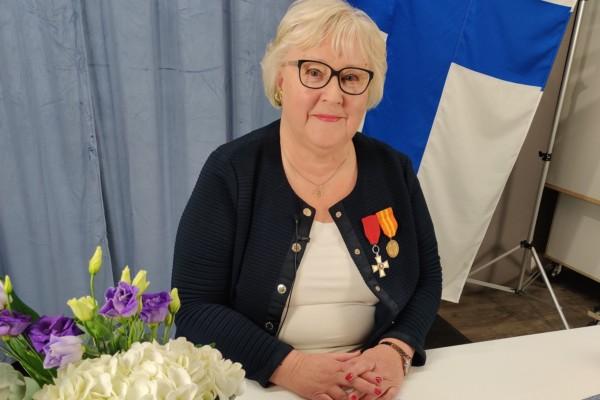 en kvinna framför Finlands flagga