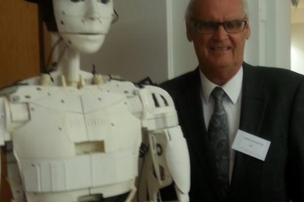 en äldre man står bredvid en humanoid robot