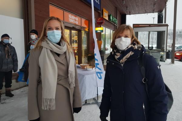 Två damer i munskydd utanför en affär