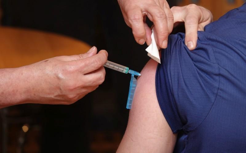 En vaccinationsspruta sticks in i en arm.