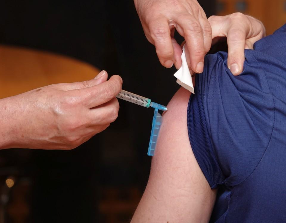 En vaccinationsspruta sticks in i en arm.
