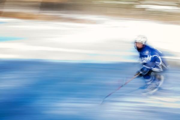 En ensam ishockeyspelare susar fram på isen.