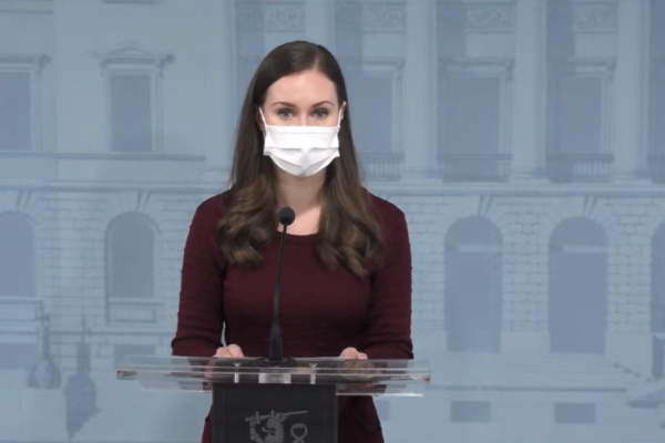 Sanna Marin iklädd munskydd talar mikrofon på presskonferens.