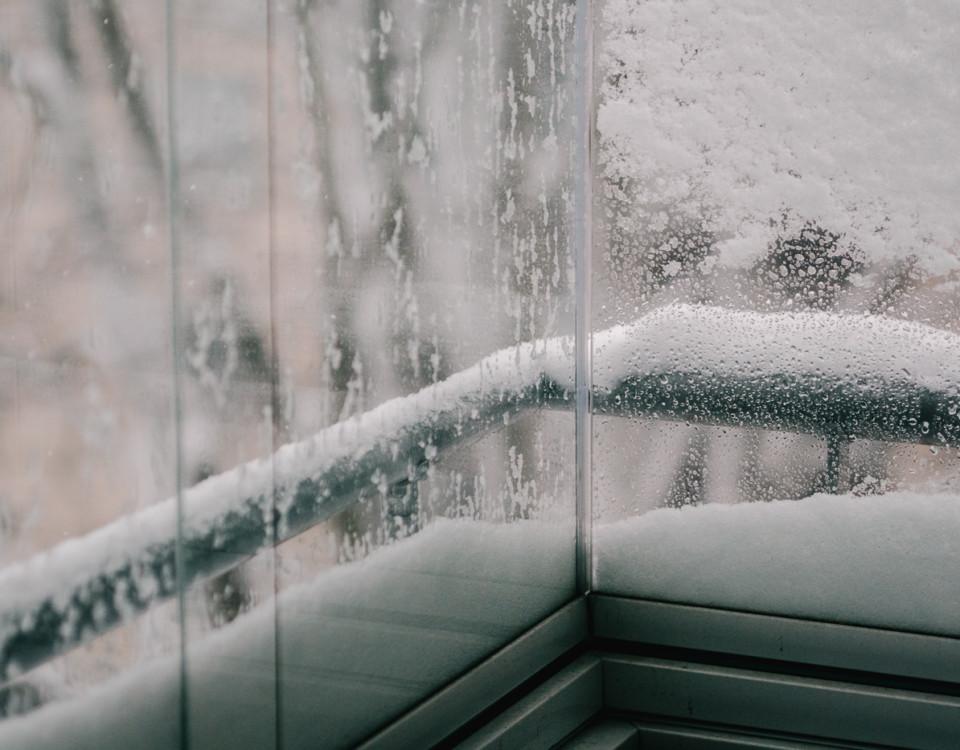 Snö samlat på utsidan av balkongglas
