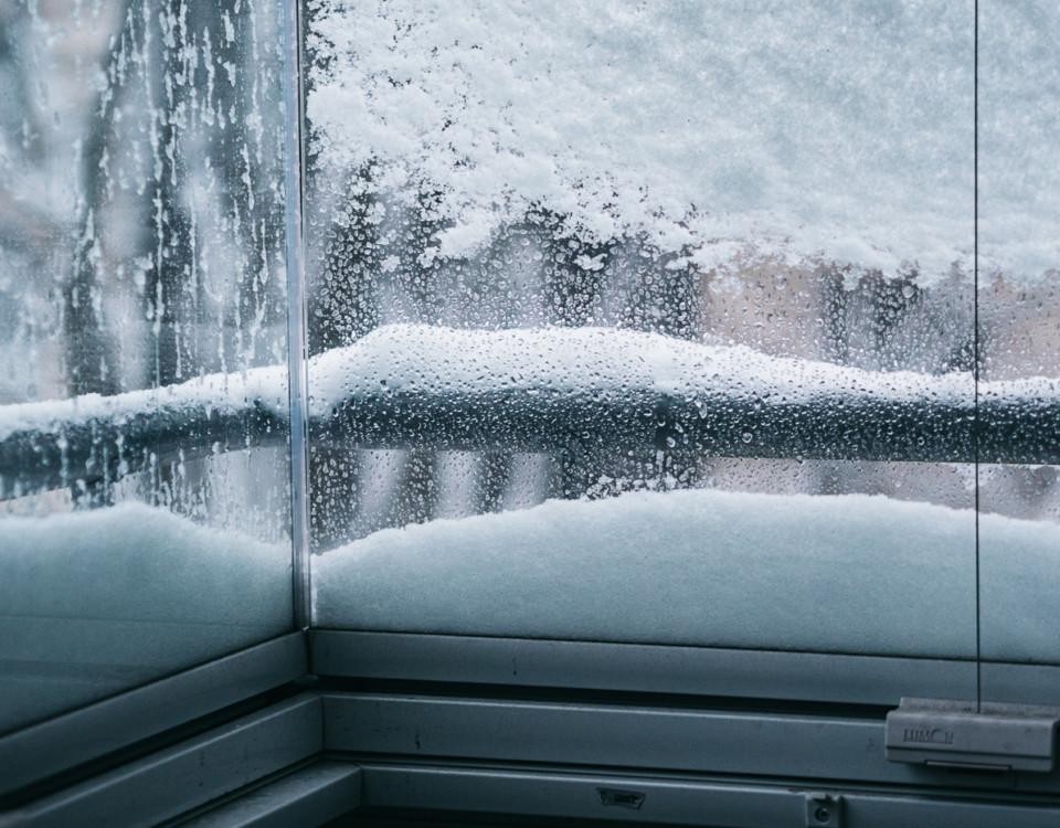 Snö samlat på utsidan av balkongglas