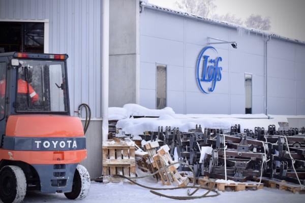 En företagshall omgiven av snö. Utanför står en liten traktor.