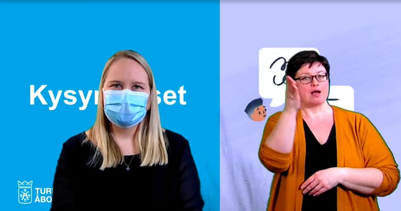 Skärmdump på Jutta Peltoniemi iförd ansiktsmask med teckenspråkstolk i bakgrunden.
