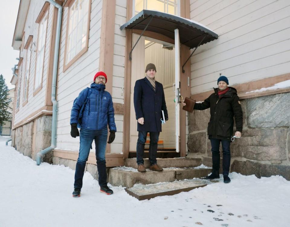Tre män står vid skoltrappa