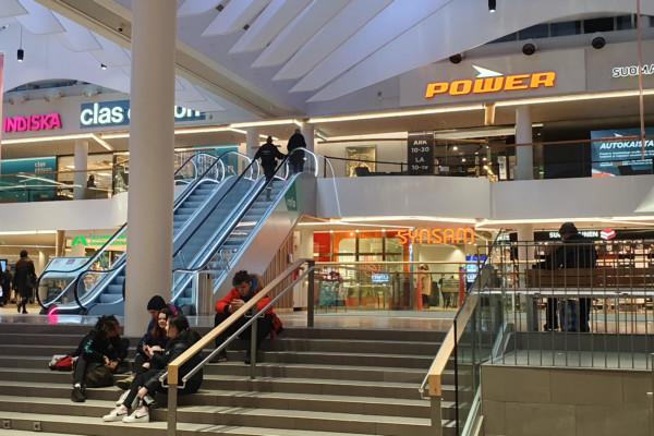 Unga personer sitter på trappan i ett köpcentrum.