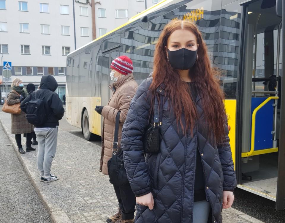 ung kvinna med munskydd utanför buss