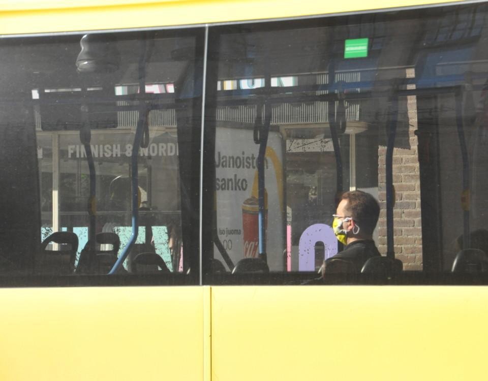 bussresenär försedd med munskydd sitter i en buss