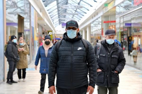 en man med munskydd i ett köpcenter