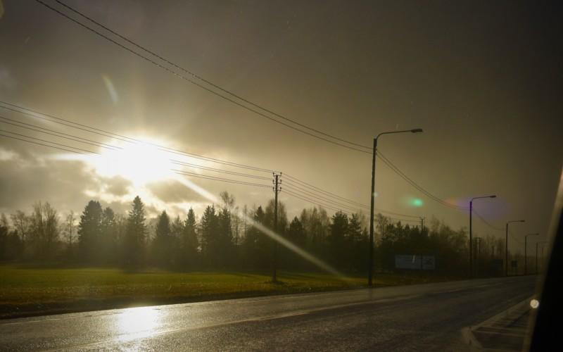 solen skiner igenom molnen på en regning landsväg