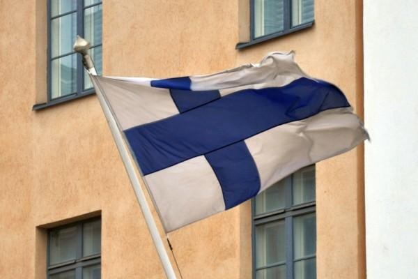 Finlands flagga vajar i flaggstång på husvägg