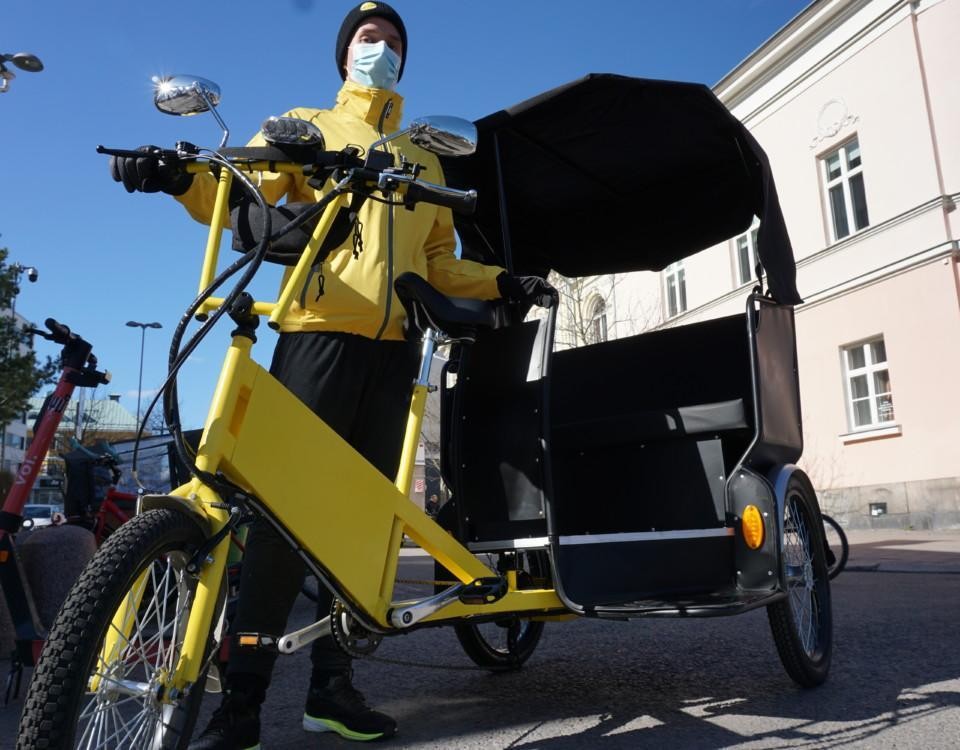 en gul cykelriksha och en gulklädd chaufför som står vid den