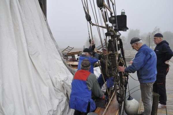 Fem män hissar en segelskutas segel