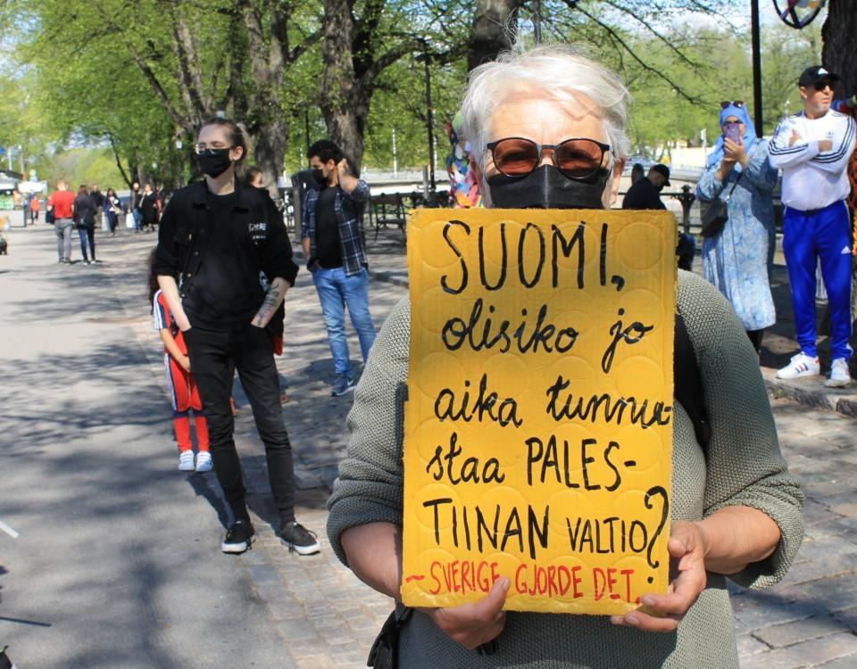 Kvinna som håller upp en skylt med uppmaningen att Finland ska erkänna palestina som en självständig stat.