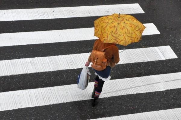 Människa med paraply går över gatan