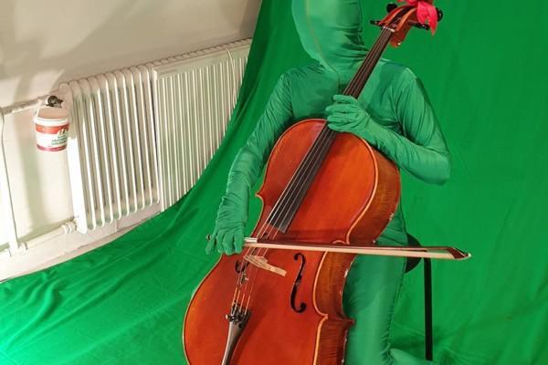 grönklädd figur spelar cello