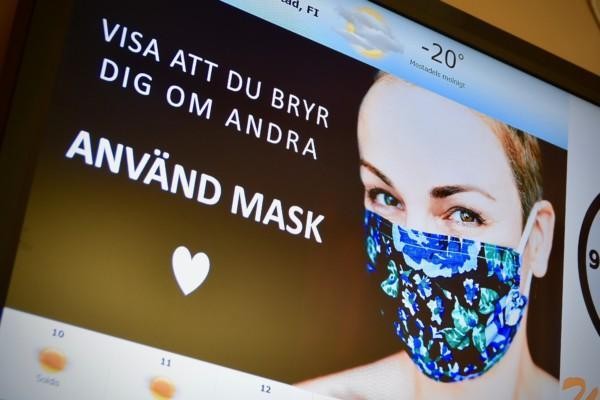 en kvinna med munskudd på en bildskärm med texten "använd mask"