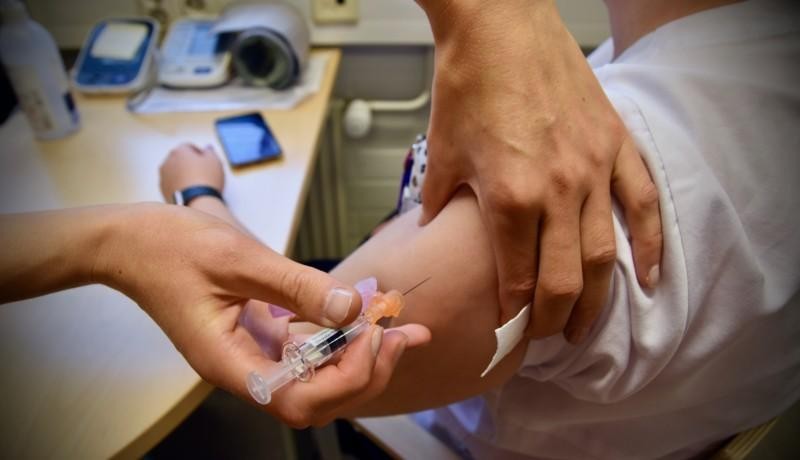 En skötare sticker in en nål i en arm