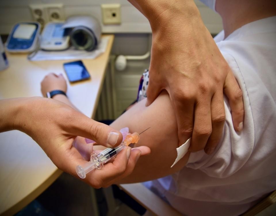 En skötare sticker in en nål i en arm