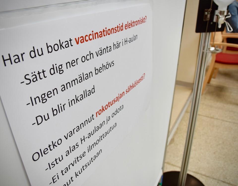 En illustrationsbild med en skylt med instruktioner om coronavaccinering.