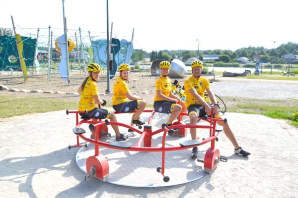 fyra gulklädda cyklister i en barnkarusell