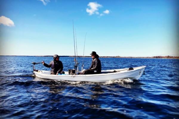 två män med kastspön i en liten båt på sjön