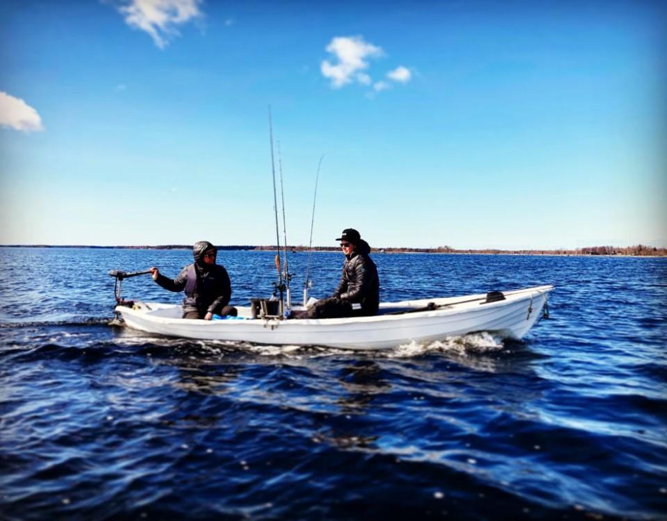 två män med kastspön i en liten båt på sjön