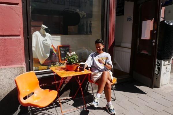 En ung kvinna sitter i solskenet utanför en second hand-affär.