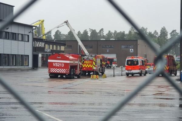 Flera brandbilar utanför en produktionsanläggning. Regnigt och grått.