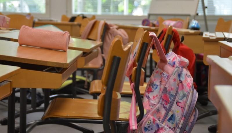 Skolväskor som hänger på stolar i ett klassrum.