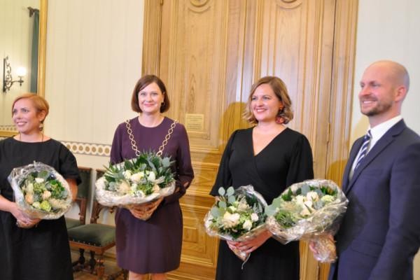 Tre kvinnor och en man med blommor i händerna