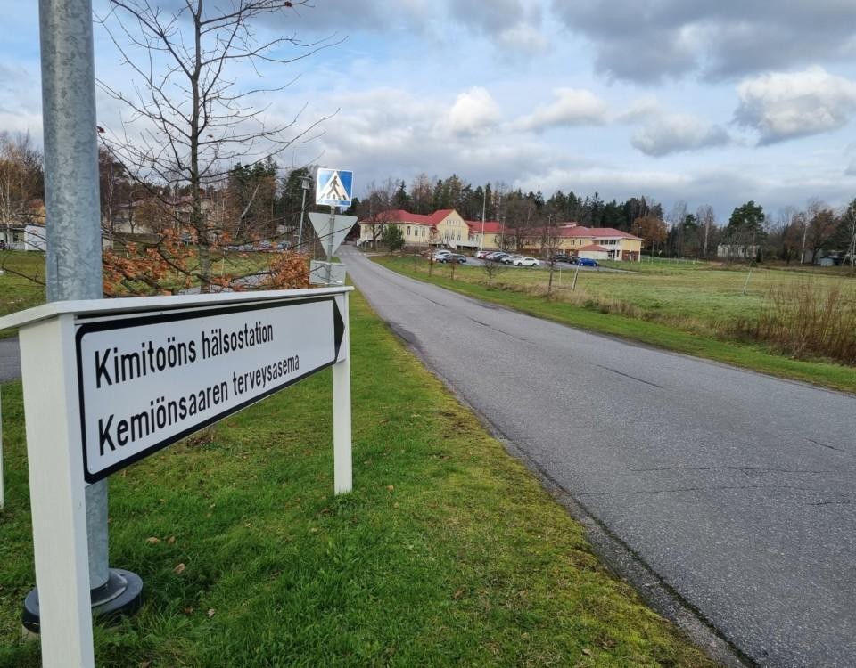 Skylt: Kimitoöns hälsovård och i bakgrunden gult vårdkomplex