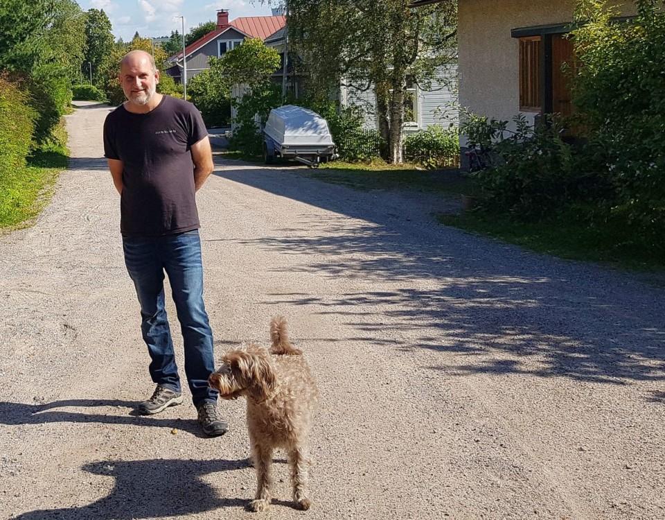 en man står på en grusväg med en hund