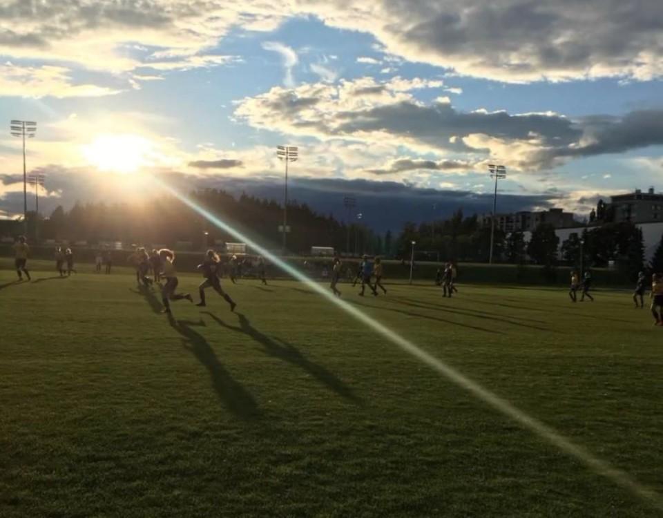 fotbollsplan med spelare i solnedgång
