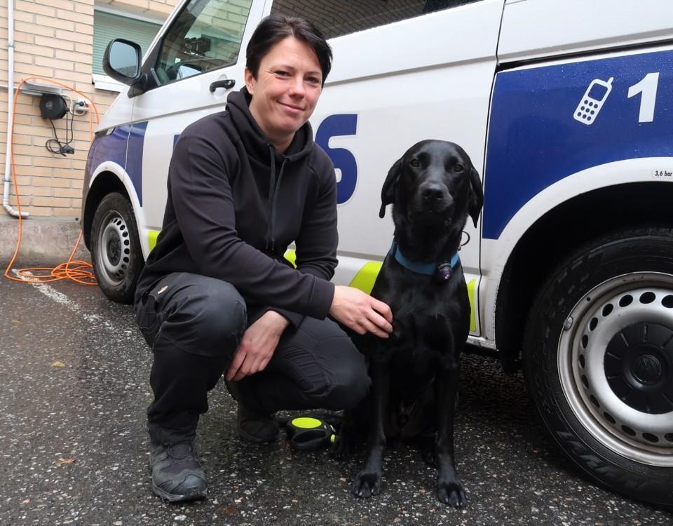 Bild av en hund och en tränare framför en polisbil.