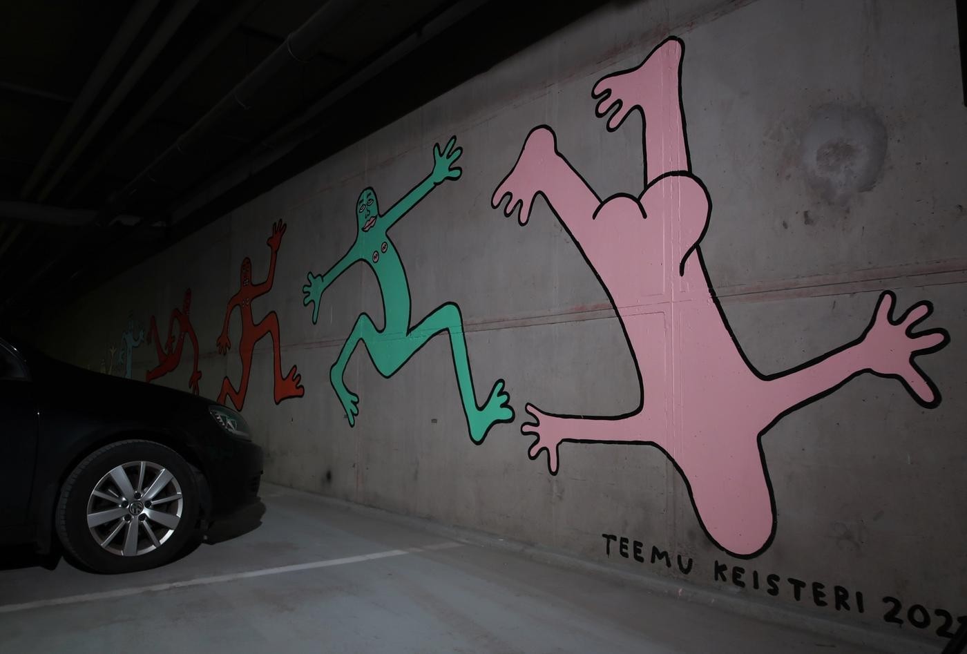Bild av färgranna nakna figurer som pryder en vägg i en parkeringshall.