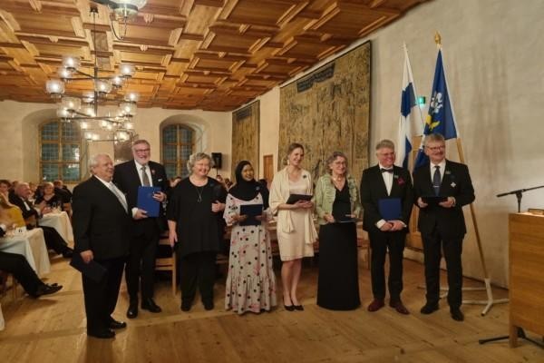 åtta människor på rad, i festliga kläder, de fotograferas i Åbo slott