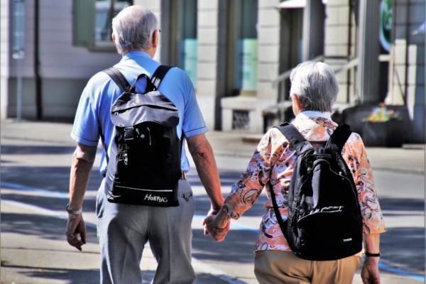 En äldre man och en kvinna som går hand i hand.