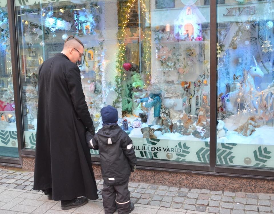 Pappa och barn ser på Stockmanns julfönster tillsammans.