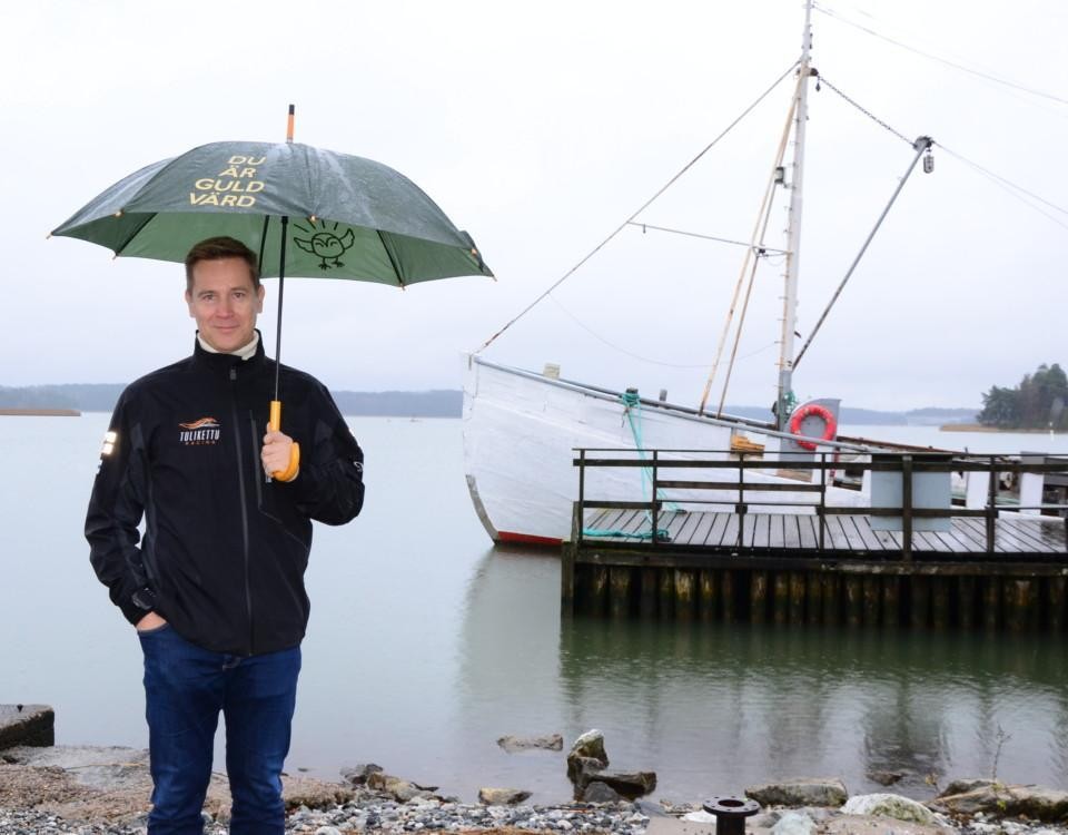 en man med ett paraply står framför en båt