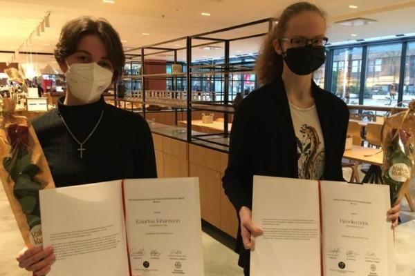 Två unga flickor visar upp varsitt diplom