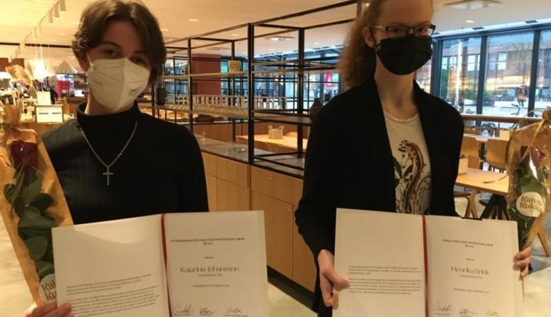 Två unga flickor visar upp varsitt diplom