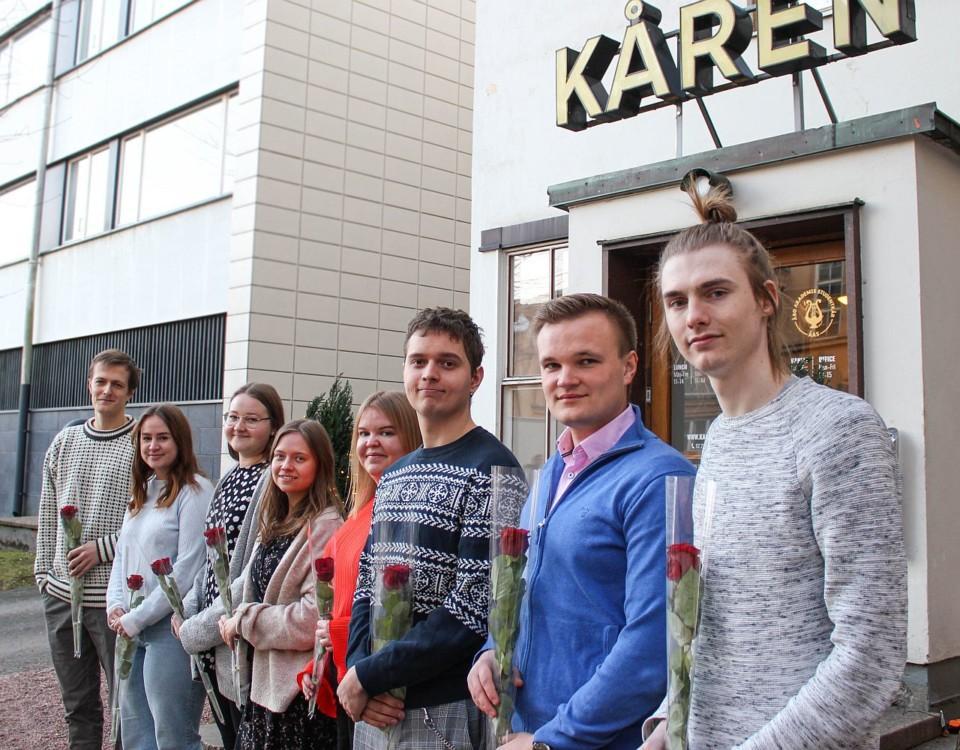 Ungdomar med rosor i handen står framför ett hus