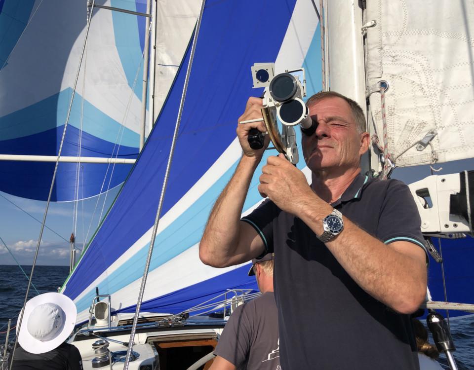 Man ombord på en båt med en sextant i handen.