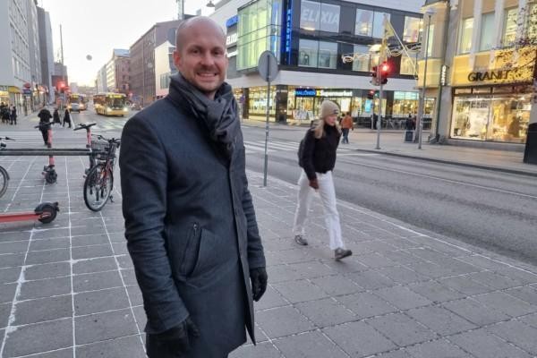 ung man står leende på trottoar i Åbo centrum