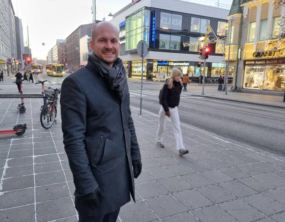 ung man står leende på trottoar i Åbo centrum