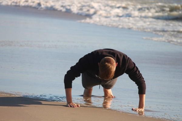ung person gör armhävning på en strand
